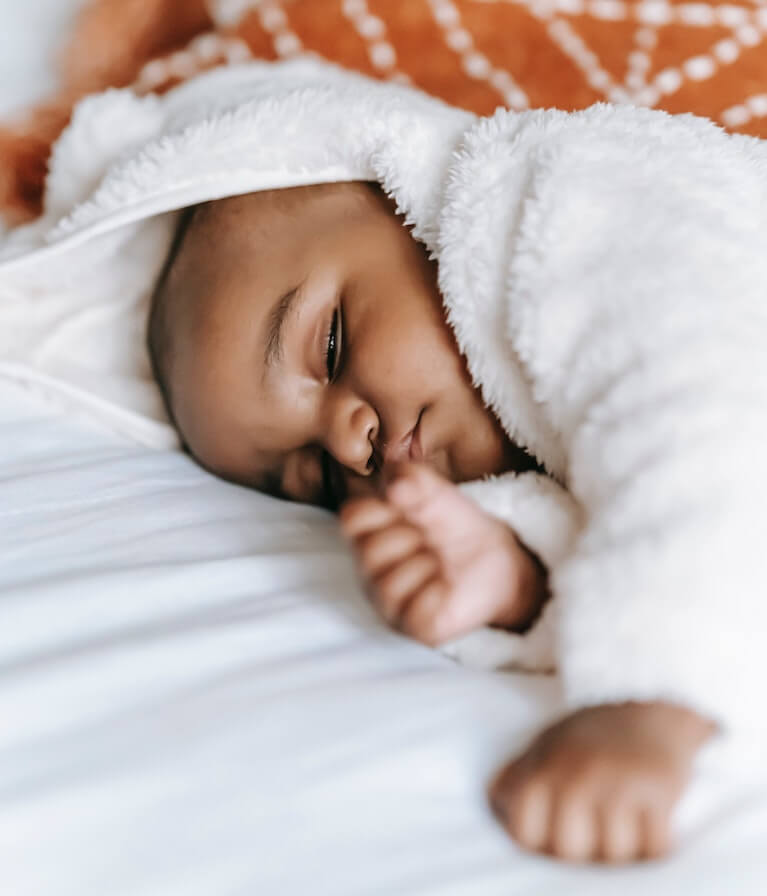 Baby sleeping in a white, soft onesie